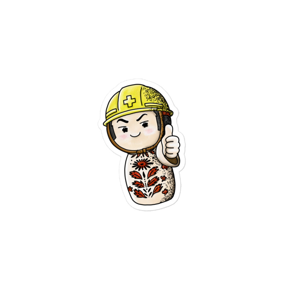 Playful JapPop sticker of a Japanese Kokeshi doll wearing a helmet inspired by traditional wooden dolls